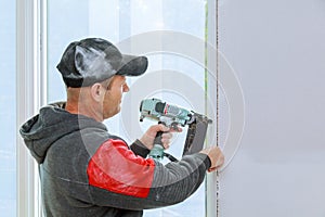 Carpenter using brad nail gun complete trim window