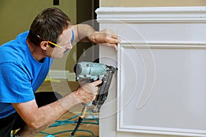 Carpenter using a brad nail gun to complete framing trim