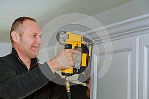 Carpenter using brad nail gun to Crown Moulding on kitchen cabinets framing trim,