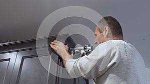 Carpenter using brad nail gun to Crown Moulding on kitchen cabinets framing trim,