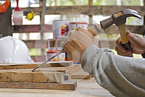 Carpenter using chisel and hammer in his hand with plank.Close up