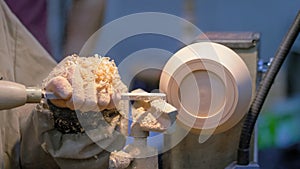 Carpenter using chisel for shaping piece of wood on lathe - close up view