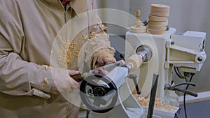 Carpenter using chisel for shaping piece of wood on lathe at workshop: close up