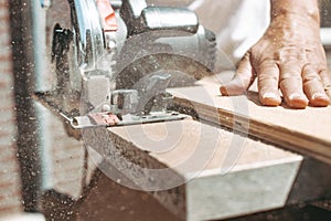 Carpenter using circular power saw for cutting wood