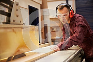 Carpenter Using Circular Saw In Carpentry Workshop