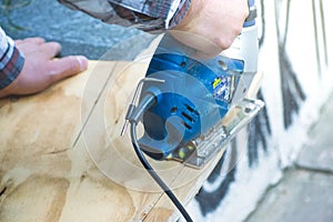 Carpenter using circular saw for cutting wooden board