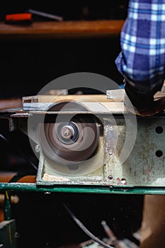 Carpenter using circular saw cutting wooden board in wood workshop