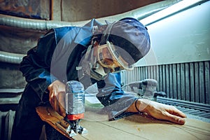 Carpenter using circular saw for cutting wooden boards.
