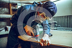 Carpenter using circular saw for cutting wooden boards.
