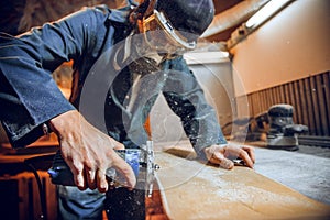 Carpenter using circular saw for cutting wooden boards.