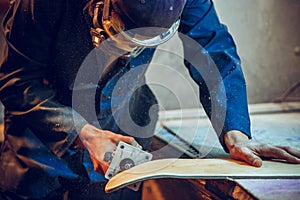 Carpenter using circular saw for cutting wooden boards.