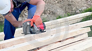 Carpenter using circular saw for cutting wooden plank while building wooden frame house.