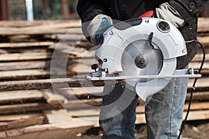 Carpenter Using Circular Saw works outdoors