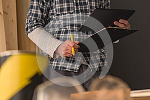Carpenter using digital tablet and clipboard notepad