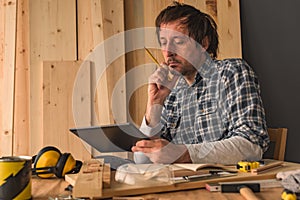 Carpenter using digital tablet in small business woodwork workshop