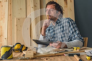 Carpenter using digital tablet in small business woodwork workshop
