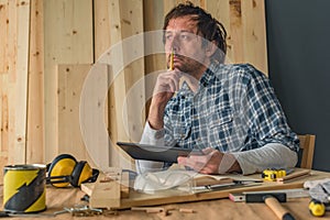 Carpenter using digital tablet in small business woodwork workshop photo