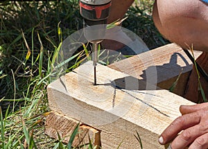 Carpenter using drill and on wood outdoor
