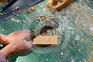 Carpenter using hammer hit the nail on wood, top view. Woodwork concept