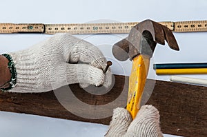 Carpenter is using hammer and nail on wood