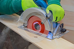 Carpenter using hand circular saw for cutting wooden boards with power tools
