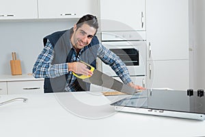 Carpenter using hand saw in kitchen