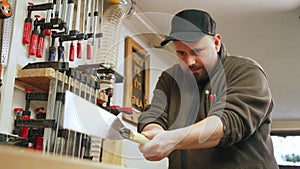 Carpenter using Japanese saw to cut wood in shop hardworking focused man at work