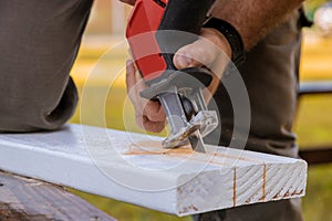 Carpenter using jigsaw for cutting wooden boards with power tools