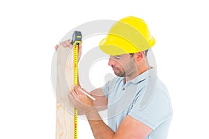 Carpenter using measure tape to mark on wooden plank