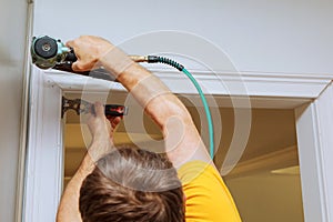 Carpenter using nail gun to moldings on windows, framing trim,