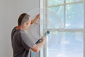 Carpenter using nail gun to moldings on windows, framing trim,