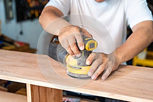 carpenter using a random orbit sander on wood in the workshop,woodworking concept , selective focus