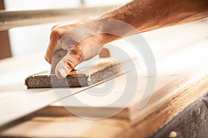 Carpenter using sander in workshop to smooth wood