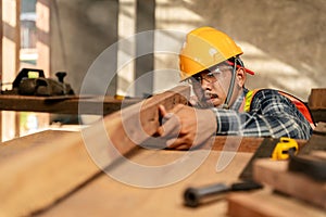 A carpenter visually examines the accuracy of the wood at construction site