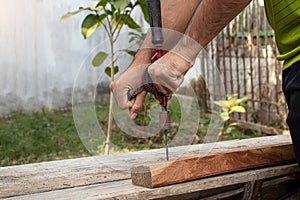 A carpenter is using an antique drill to drill wood to repair a broken table.