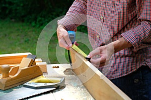 Carpenter woman using a measuring tape for check the length of timber plank. Woodworking concept