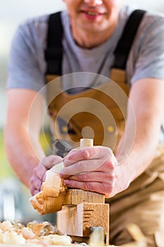 Carpenter with wood planer and workpiece in carpentry
