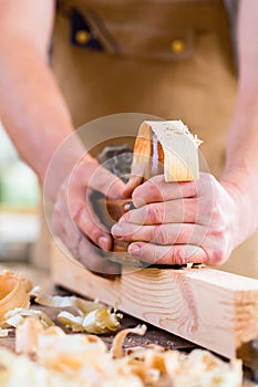 Carpenter with wood planer and workpiece in carpentry