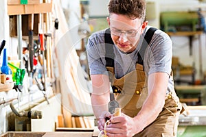 Carpenter with wood planer and workpiece in carpentry