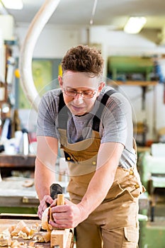 Carpenter with wood planer and workpiece in carpentry