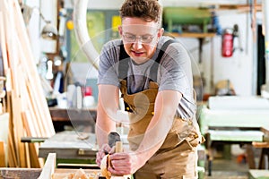 Carpenter with wood planer and workpiece in carpentry