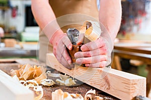 Carpenter with wood planer and workpiece in carpentry photo