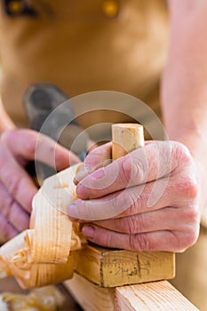 Carpenter with wood planer and workpiece in carpentry