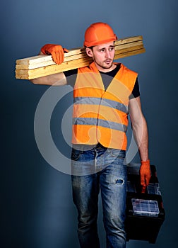 Carpenter, woodworker, labourer, builder on busy face carries wooden beams on shoulder. Construction and woodworking