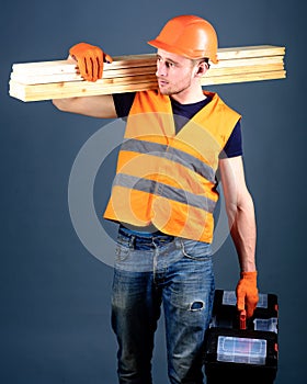 Carpenter, woodworker, labourer, builder on busy face carries wooden beams on shoulder. Man in helmet, hard hat holds