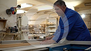 Carpenter at work at his workshop, wood processing on a woodworking machine