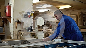 Carpenter at work at his workshop, wood processing on a woodworking machine