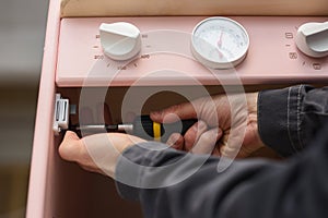 Carpenter at work making play kitchen oven. Fixing magnetic lock with screwdriver