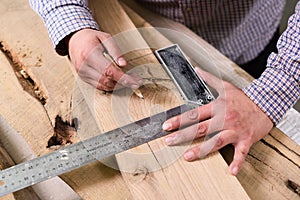 Carpenter at work. Man measures and marks wood board with metal