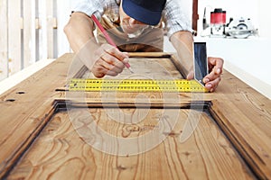 Carpenter at work measures with the setsquare and pencil on wood